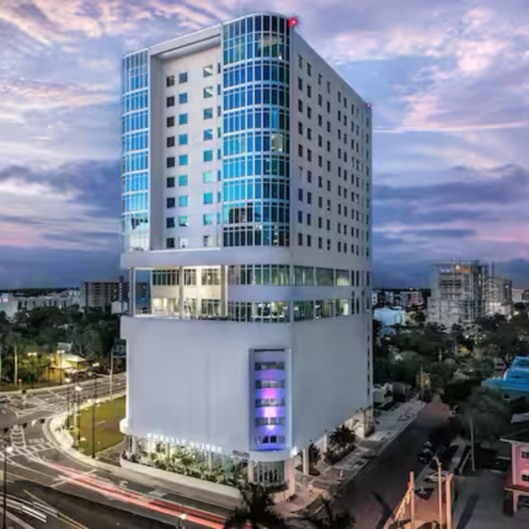 Exterior of Embassy Suites by Hilton in downtown Sarasota at dusk.